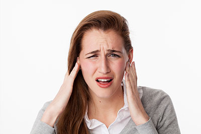 The image shows a woman with her hand on her head, possibly expressing discomfort or stress, with a concerned facial expression.