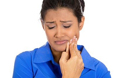 A woman with her eyes closed, looking upwards, holding her nose with her hand, with an expression of concern or discomfort on her face.