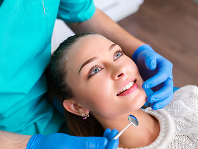 A woman receiving dental care from a professional seated behind her, with a focus on the dental equipment and the patient s expression.